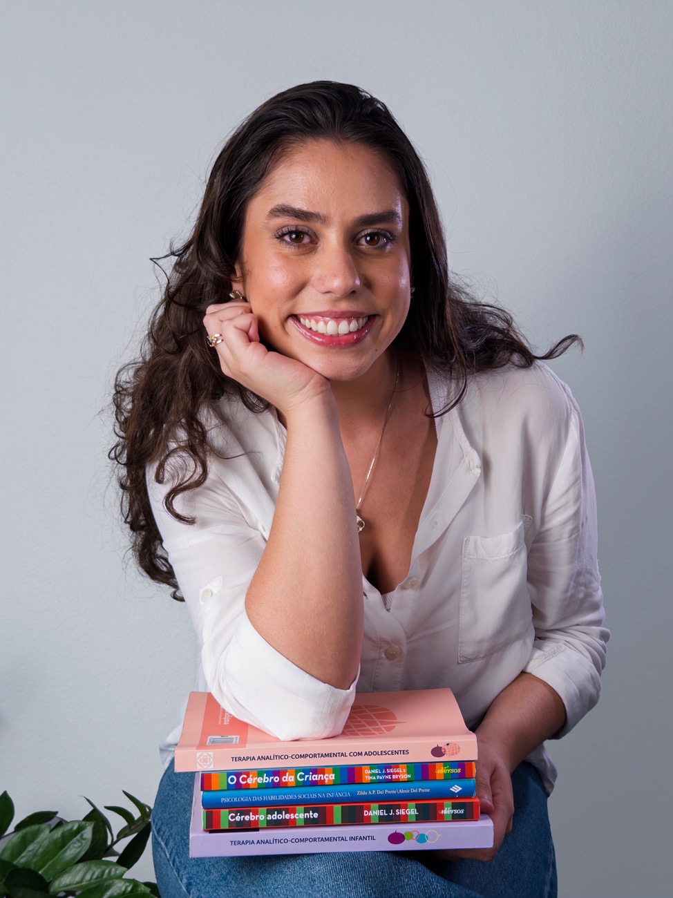 Retrato de ensaio sorrindo com livros no colo